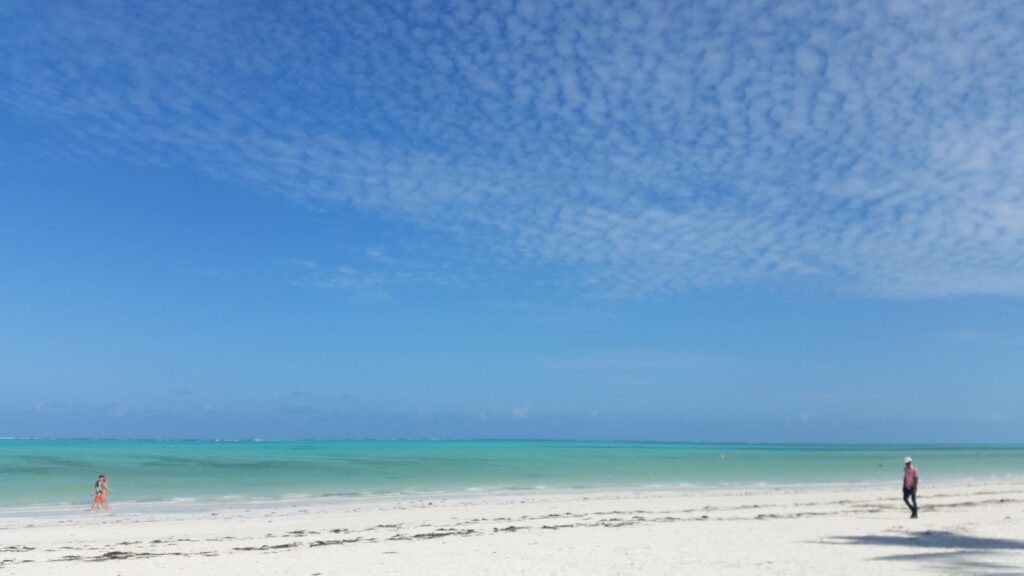 A kitesurfer gliding across the shallow lagoon at Paje Beach, Zanzibar, under clear skies