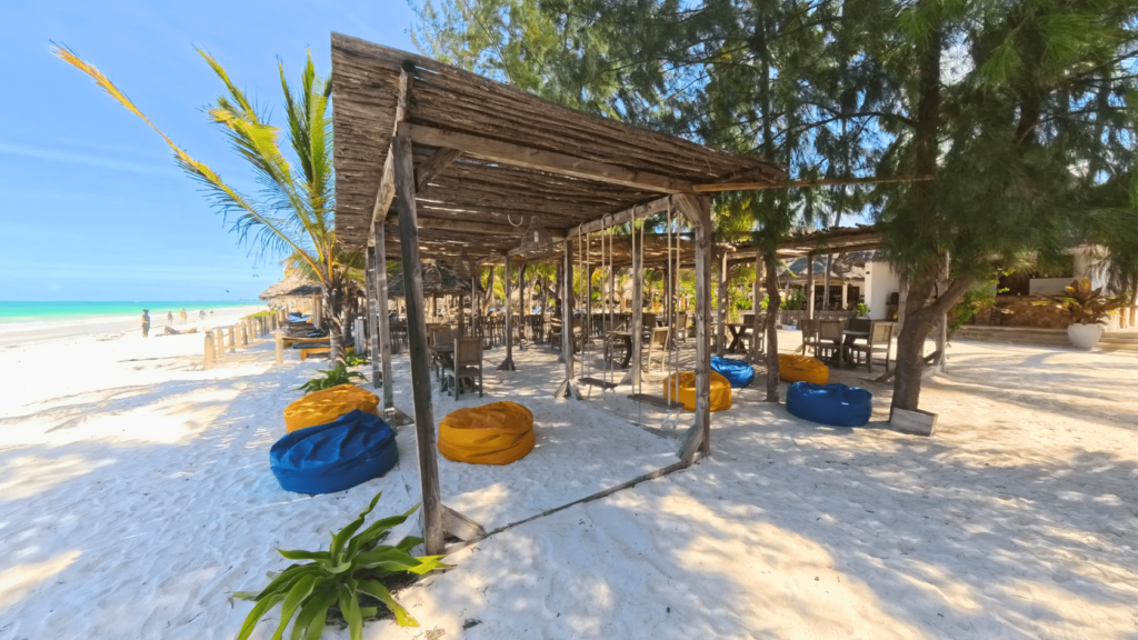 Image of Kite Bar on the beach:
"Kite Bar on Paje Beach, Zanzibar, offering a perfect spot to relax and enjoy refreshments after a kitesurfing session."

Image of kitesurfers enjoying drinks at the Kite Bar:
"Kitesurfers relaxing with drinks at the Kite Bar, sharing stories and enjoying the stunning ocean views on Paje Beach."

Image of refreshing drinks and snacks at the Kite Bar:
"Refreshing drinks and delicious snacks served at the Kite Bar, the ideal place to refuel after kitesurfing in Zanzibar."

Image of the shaded seating area at the Kite Bar:
"Shaded seating area at the Kite Bar, providing a cool and comfortable place for kitesurfers to unwind on Paje Beach."