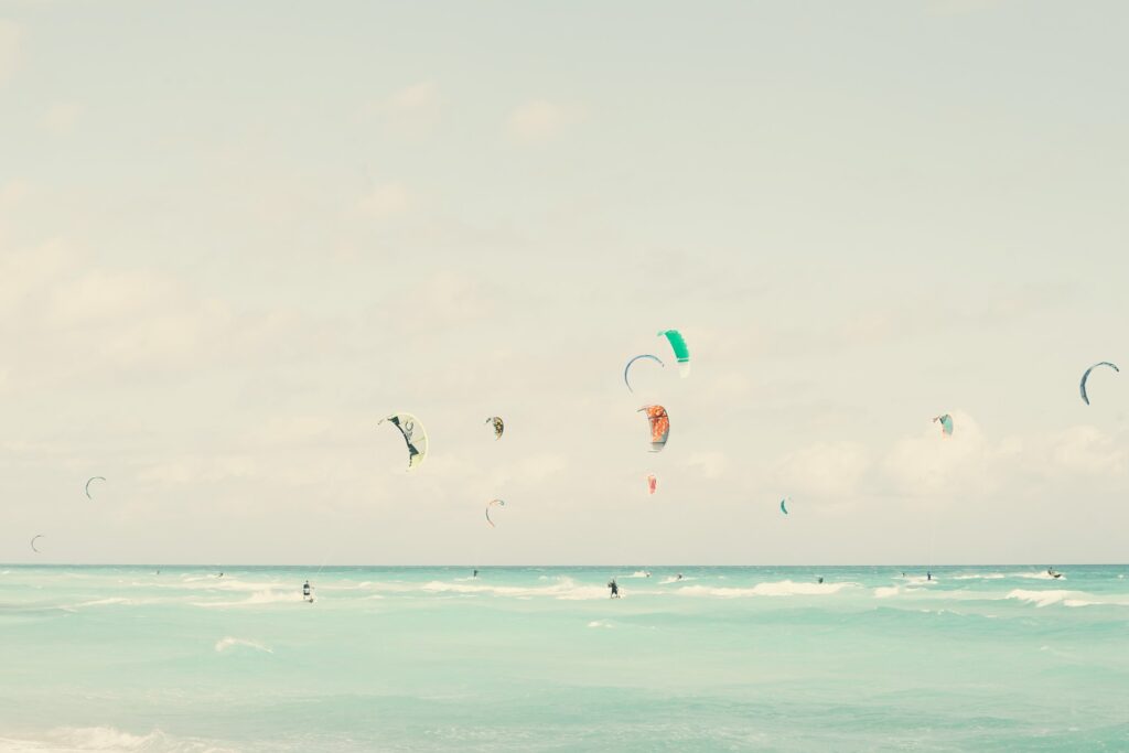 A beginner kitesurfer learning to ride the waves at Paje Beach, Zanzibar, with turquoise waters and a clear sky in the background.